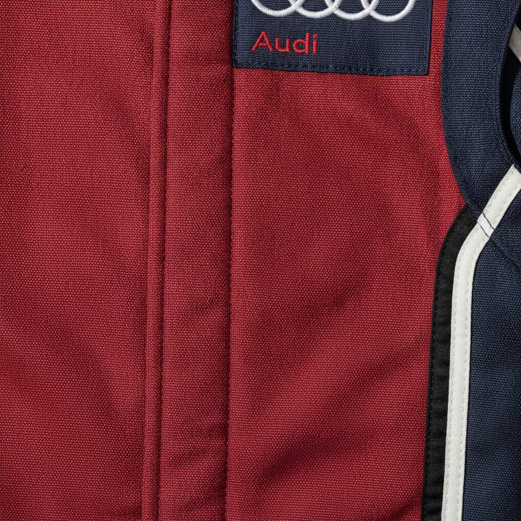 Close-up of heavy-duty, fire-retardant aramid Nomex fabric weave on a custom motorsport racing suit with premium embroidered team logo patch.